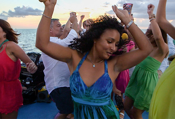 a woman dancing in a group of people on a boat