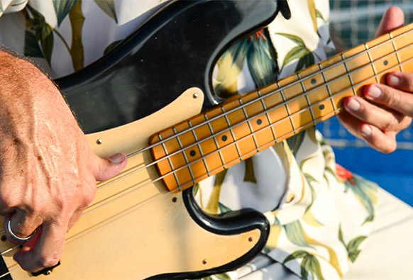 an up-close image of a man playing the bass guitar